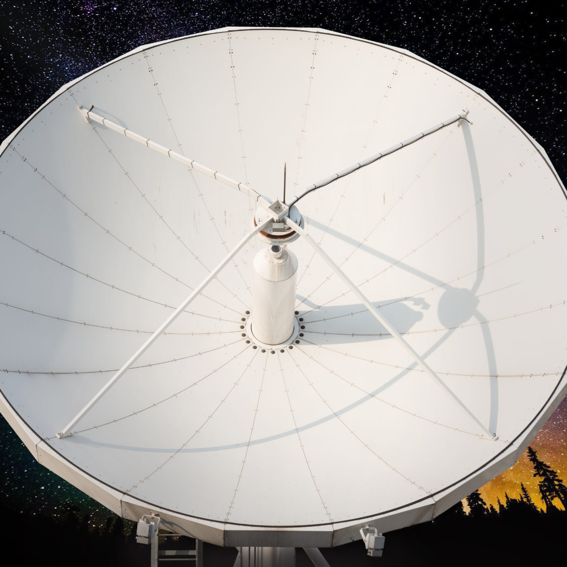 Large parabolic antenna pointed at a star-filled night sky.