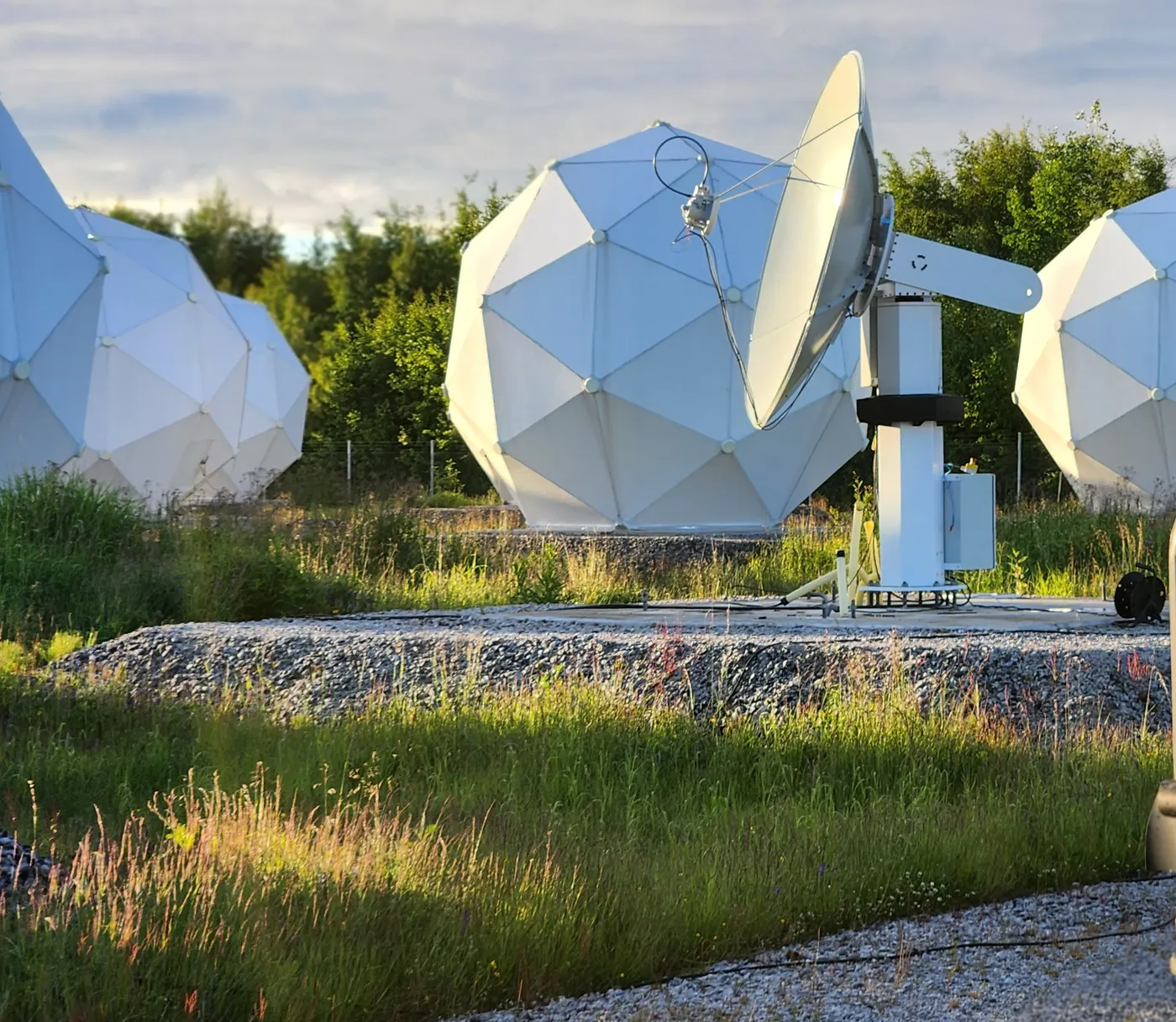 Radomes and a tracking antenna on their pads at the Arctic Space Center, Piteå, in evening light.